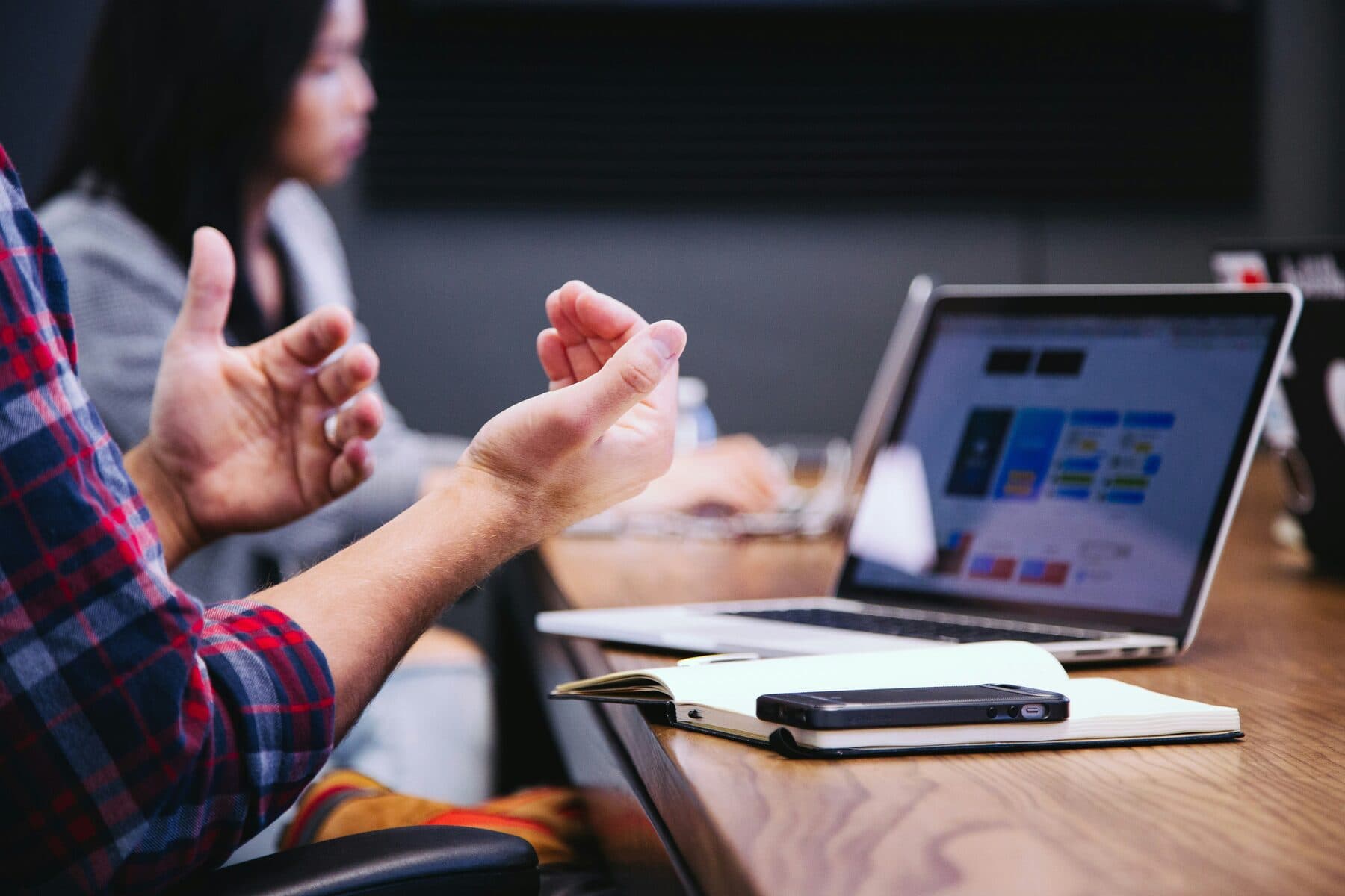 A professional gesturing while speaking during a working meeting.