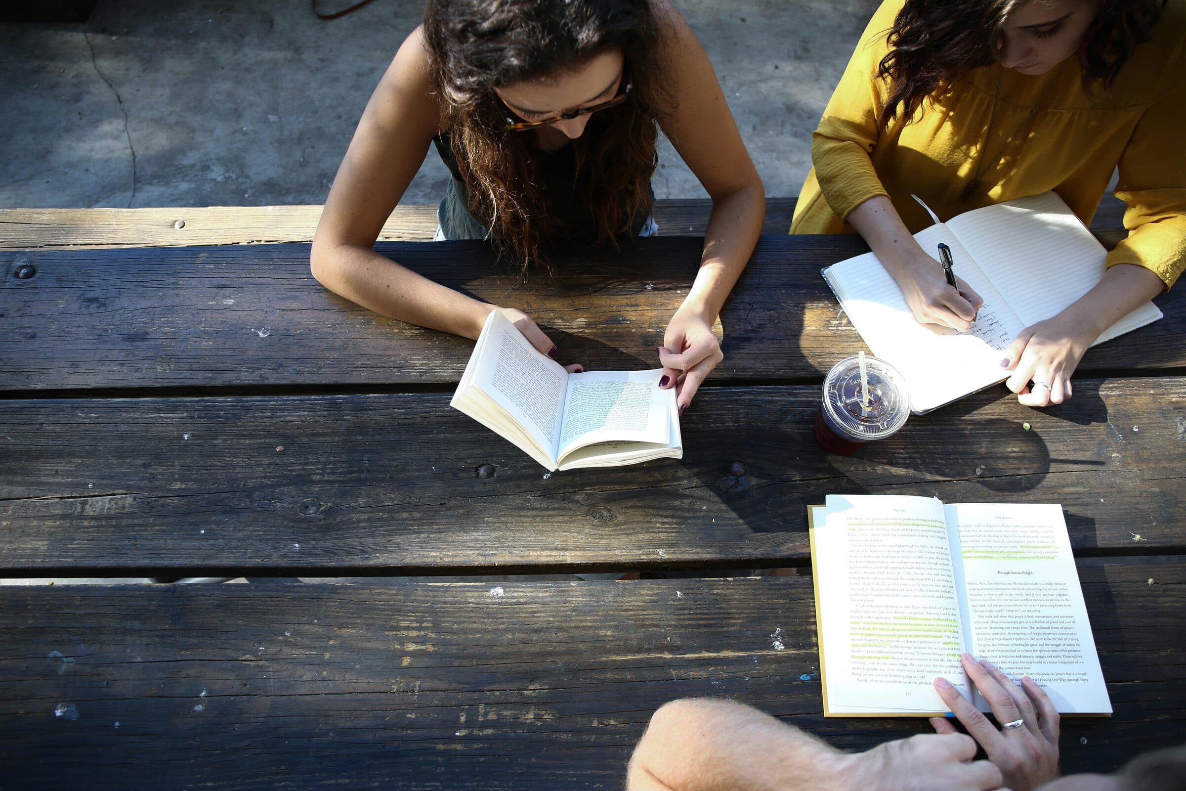 Students working through books and notes together at a table.