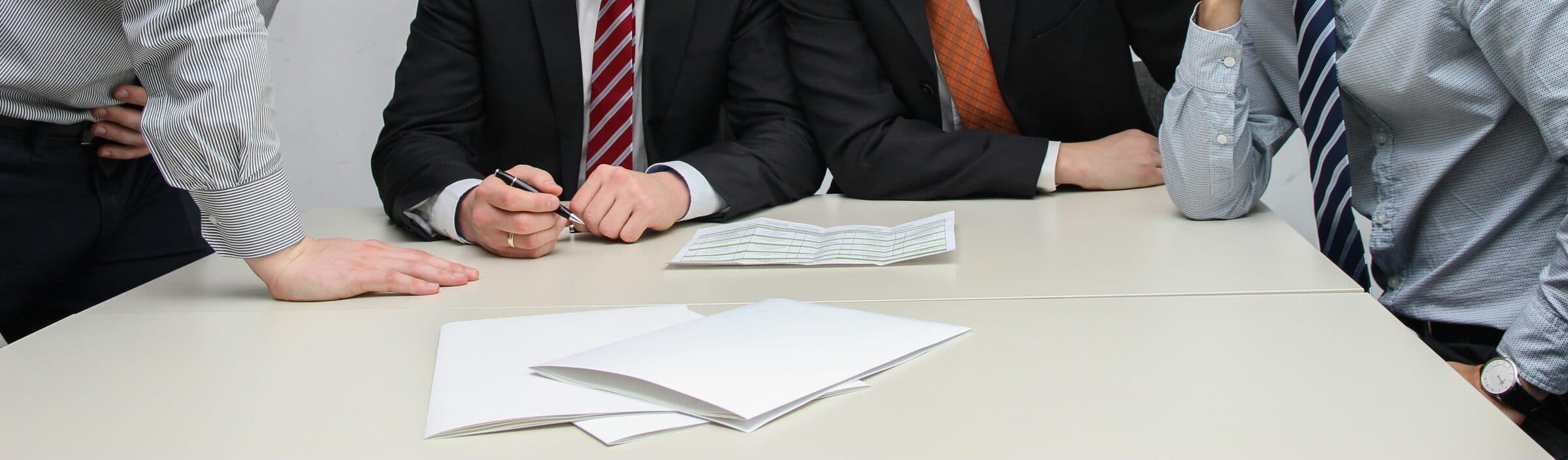 Several people leaning over a document together, examining it closely.